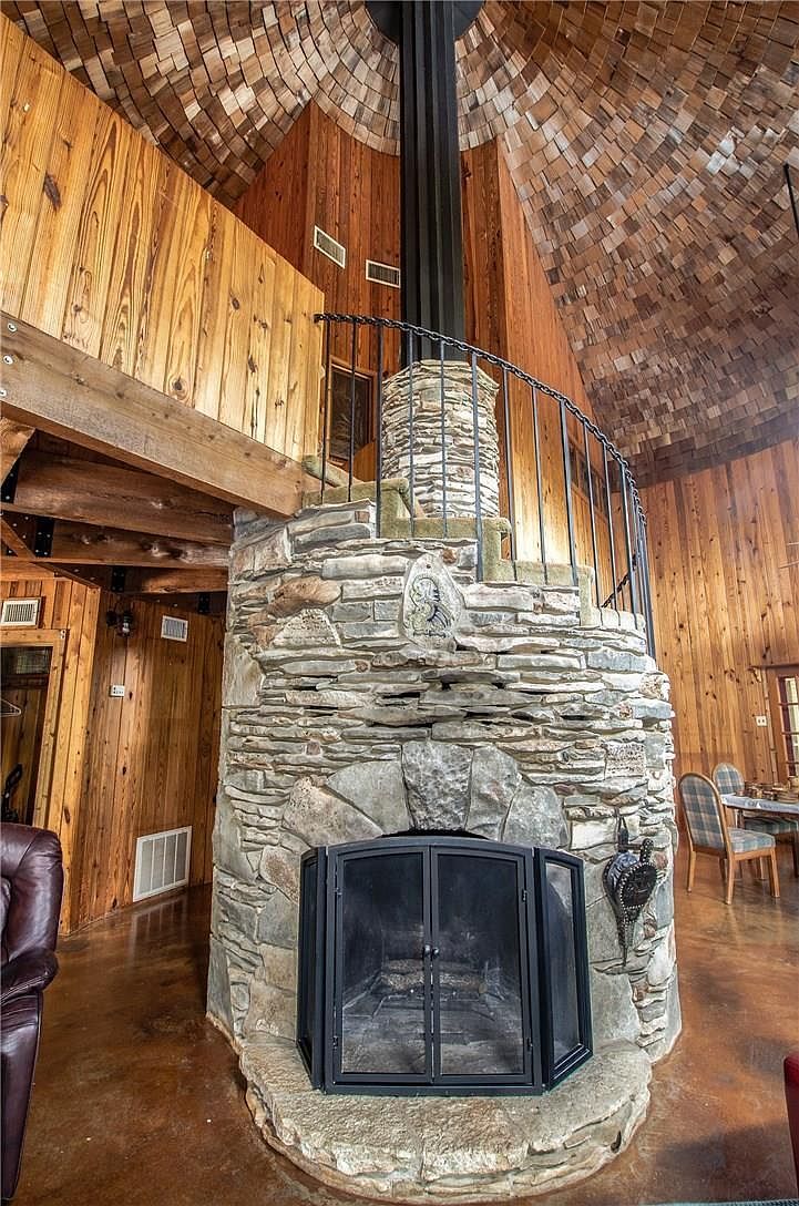 The stone fireplace inside the silo, rising through the room to the cedar shake ceiling, with the dragon carved into the stone above the firebox